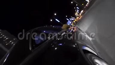 黑色温和的汽车在夜间移动在城市的街道上，汽车LED灯闪烁不同的颜色。 录像。 汽车